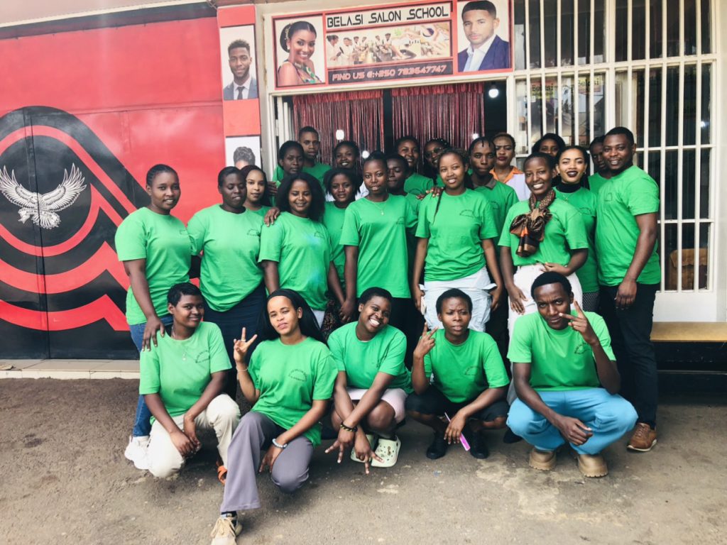 Students and teacher posing for a remembrance photo under the Belasi Saloon School Rwanda signpost, showcasing the top beauty and TVET institution led by Epiphanie MUKAYIRANGA