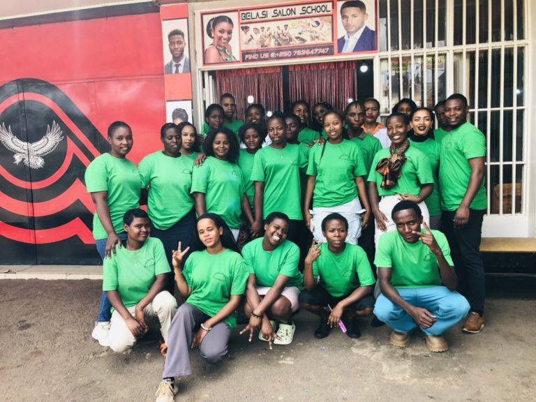 Students and teacher posing for a remembrance photo under the Belasi Saloon School Rwanda signpost, showcasing the top beauty and TVET institution led by Epiphanie MUKAYIRANGA