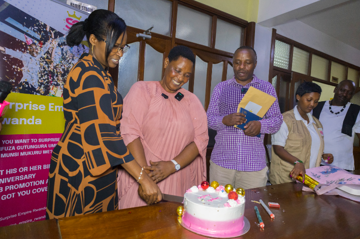 Kayitesi Emilienne cutting a celebratory cake with Agatesi Marie Laetitia, CEO of Isango Star, and Amos Byamukama, CEO of Surprise Empire Rwanda, during her Journalist of the Year award celebration.