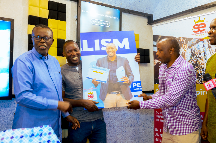 Rev. Samuel Mutabazi with Didace Niyifasha receiving a portrait of his award, accompanied by Mr. Amos Byamukama, CEO of Surprise Empire Rwanda.
