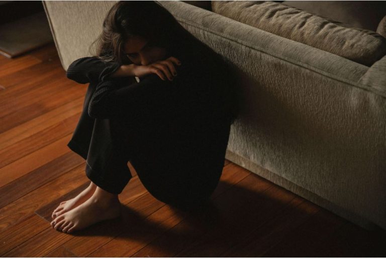 A woman showing the reasons for suicide, sitting hopeless in dark clothes.