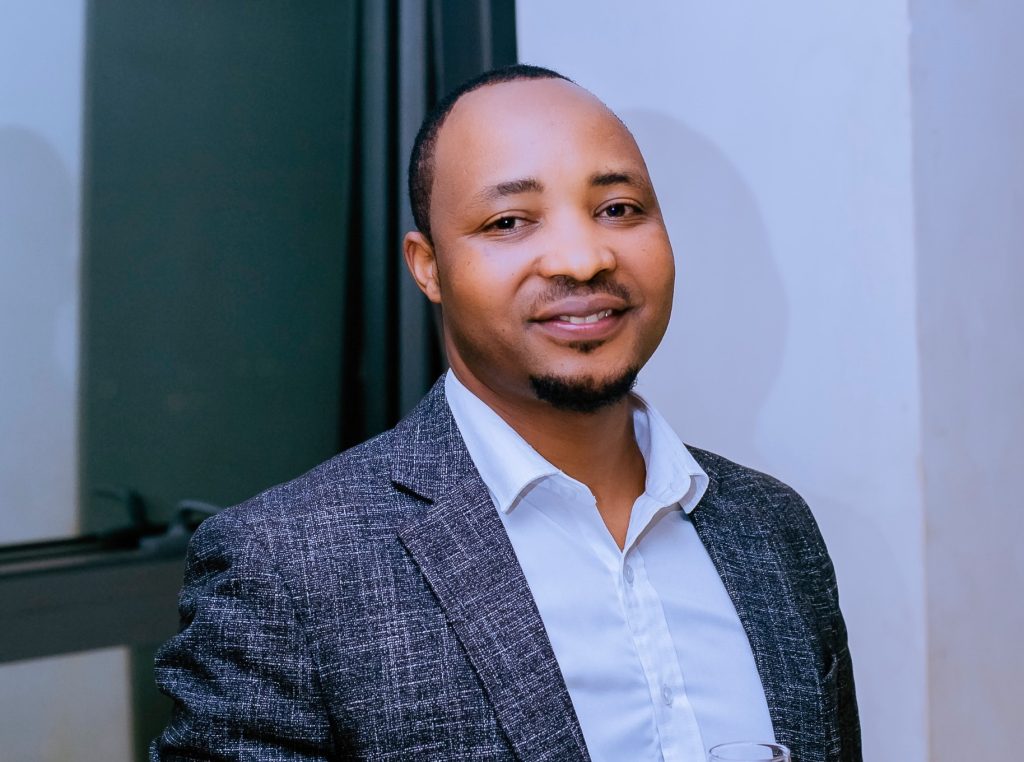 Hakizimana Jean Pierre smiles while holding a glass of champagne at his birthday celebration at L&G Restaurant.